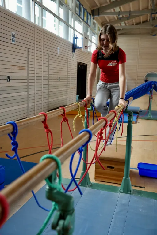 Ein M�dchen hangelt sich �ber den Barren.