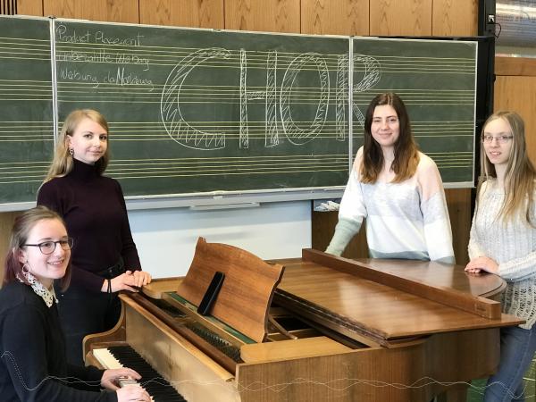 Vier Schülerinnen stehen um ein Klavier herum