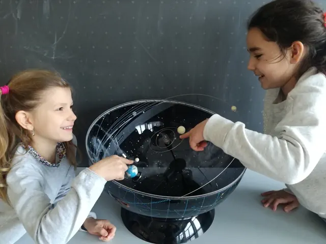 Zwei Schülerinnen betrachten Modell des Sonnensystems