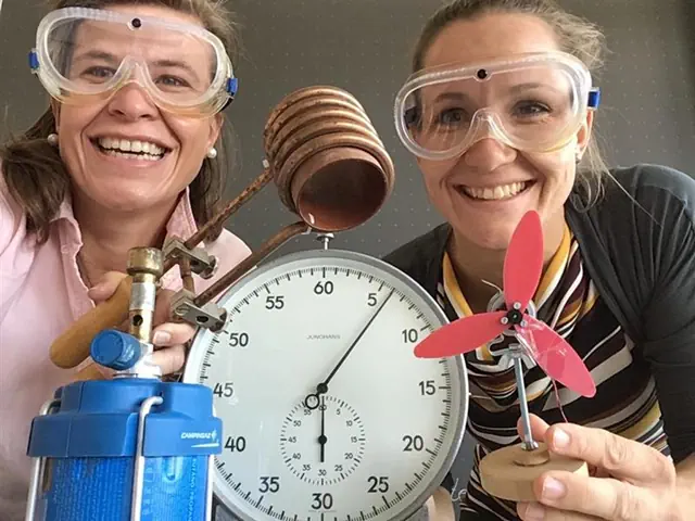 Frau Bareiß und Frau Kokot mit Chemie-Brillen, Bunsenbrenner, Stoppuhr und Ventilator